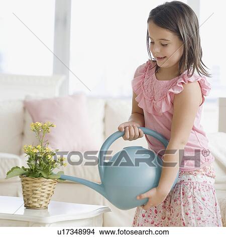 Picture - Girl watering plant indoors. Fotosearch