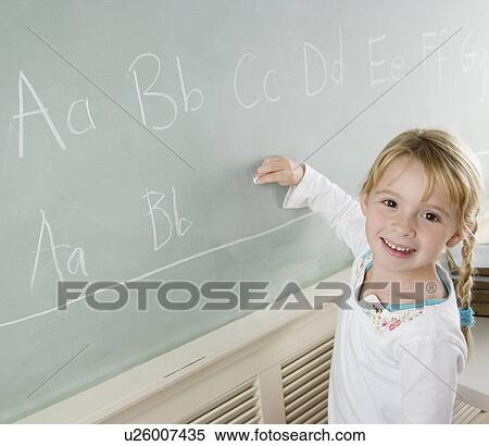 Stock Photography - Girl writing on blackboard and smiling. Fotosearch