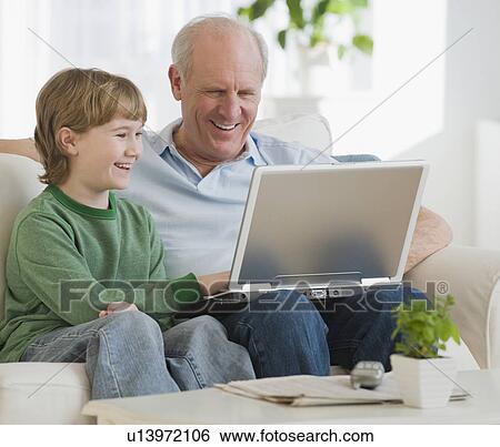Stock Photograph - Grandfather and grandson looking at laptop. Fotosearch