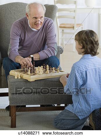 Stock Image - Grandfather and grandson playing chess. Fotosearch