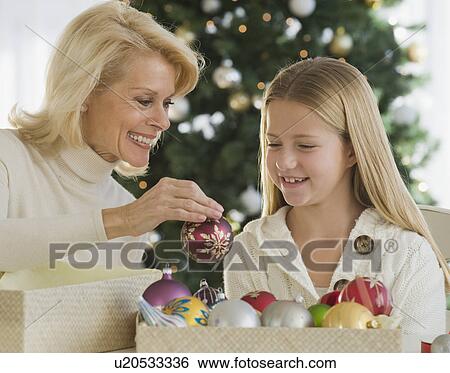 Stock Photograph - Grandmother and granddaughter looking at Christmas ornaments. Fotosearch