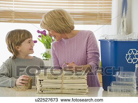 Stock Image - Grandmother and grandson recycling newspapers. Fotosearch
