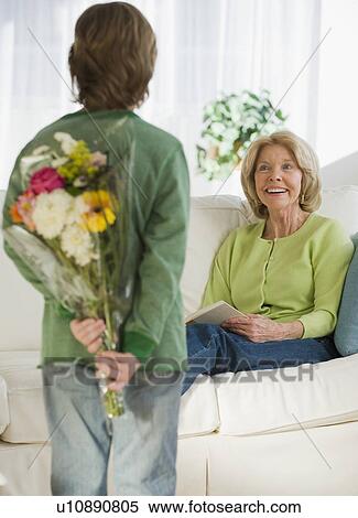 Grandson surprising grandmother with flowers View Large Photo Image Stock Photography - Grandson surprising grandmother with flowers. Fotosearch
