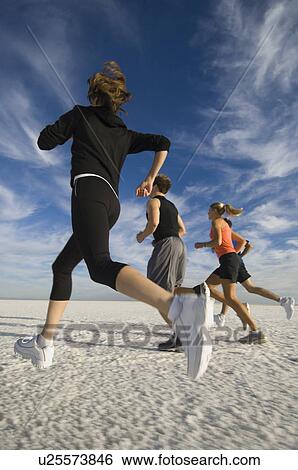Stock Photograph - Group of people running on salt flats, Utah, United States. Fotosearch