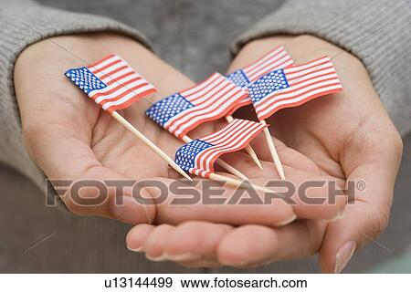Hands holding small US flags View Large Photo Image Stock Photo - Hands holding small US flags. Fotosearch
