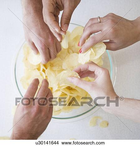 Hands reaching into bowl of chips View Large Photo Image Picture - Hands reaching into bowl of chips. Fotosearch