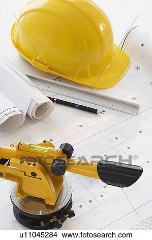 Picture - Hard hat and surveying equipment on blueprints. Fotosearch