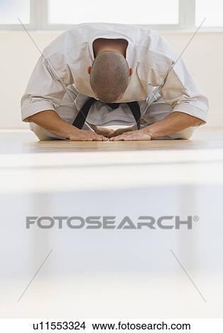 Picture - Hispanic male karate black belt bowing. Fotosearch