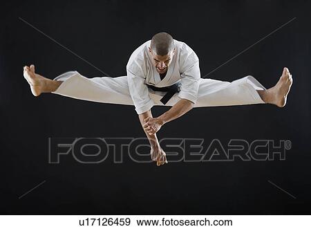 Stock Photo - Hispanic male karate black belt jumping in air. Fotosearch