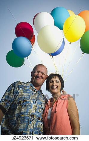 Low angle view of couple with balloons View Large Photo Image Stock Image - Low angle view of couple with balloons. Fotosearch