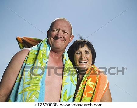 Low angle view of couple with beach towels View Large Photo Image Stock Photo - Low angle view of couple with beach towels. Fotosearch