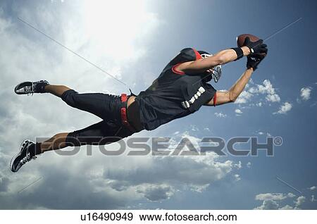Stock Photo - Low angle view of football player jumping. Fotosearch