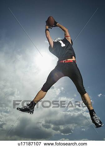 Low angle view of football player jumping View Large Photo Image Stock Photo - Low angle view of football player jumping. Fotosearch