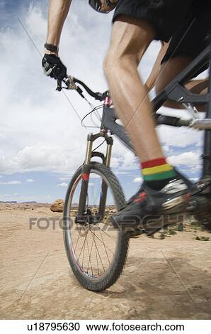 Stock Image - Low angle view of man riding mountain bike. Fotosearch