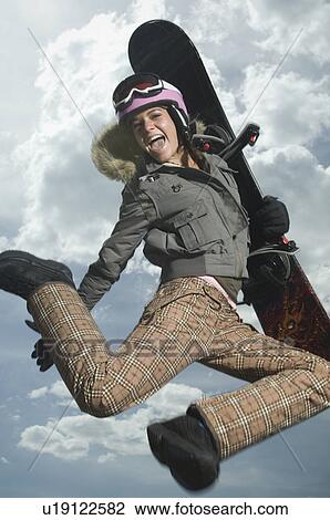 Stock Image - Low angle view of snowboarder jumping. Fotosearch