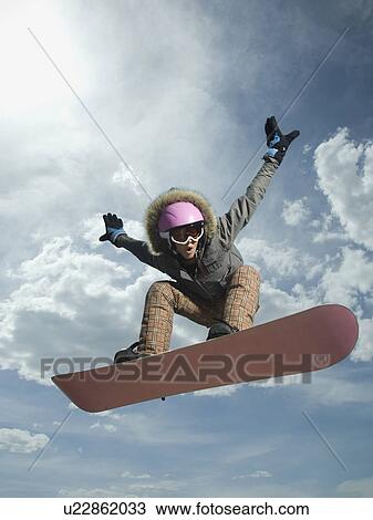 Stock Image - Low angle view of snowboarder jumping. Fotosearch