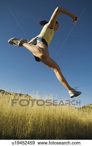 Stock Photo - Low angle view of woman jumping, Salt Flats, Utah, United States. Fotosearch