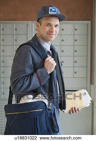 Stock Image - Male postal worker carrying mailbag. Fotosearch