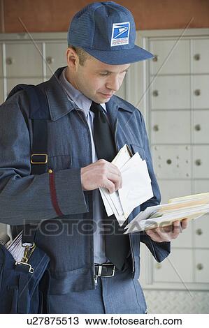 Stock Image - Male postal worker looking at mail. Fotosearch