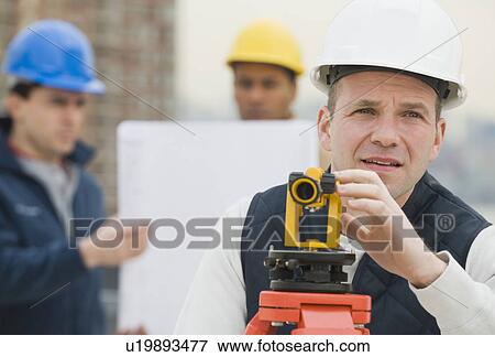 Stock Photo - Male surveyor looking through measuring device. Fotosearch