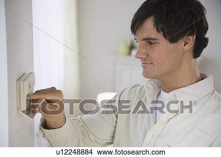 Man adjusting digital thermostat View Large Photo Image Picture - Man adjusting digital thermostat. Fotosearch