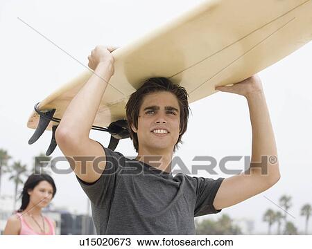 Man carrying surfboard on head View Large Photo Image Stock Image - Man carrying surfboard on head . Fotosearch