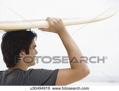 Stock Photo - Man carrying surfboard on head . Fotosearch