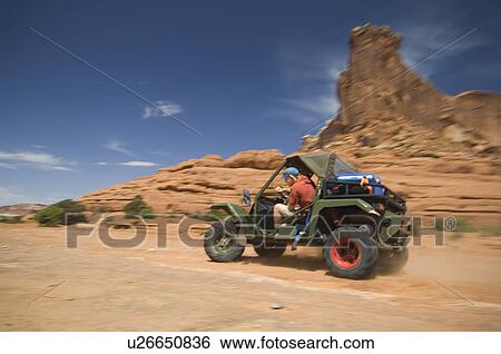 Stock Photograph - Man driving off-road vehicle in desert. Fotosearch