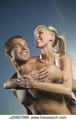 Stock Photo - Man giving girlfriend piggyback ride. Fotosearch