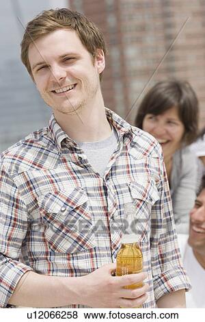 Stock Photo - Man holding beer at party. Fotosearch