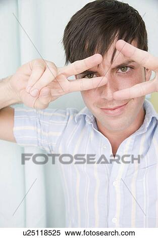 Man holding fingers in front of eyes View Large Photo Image Stock Photography - Man holding fingers in front of eyes. Fotosearch