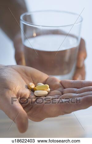Man holding medication and glass of water View Large Photo Image Stock Image - Man holding medication and glass of water. Fotosearch
