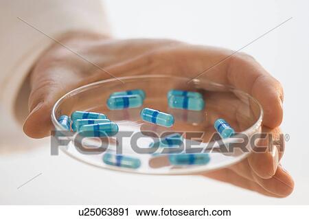Stock Image - Man holding prescription medication in Petri dish. Fotosearch