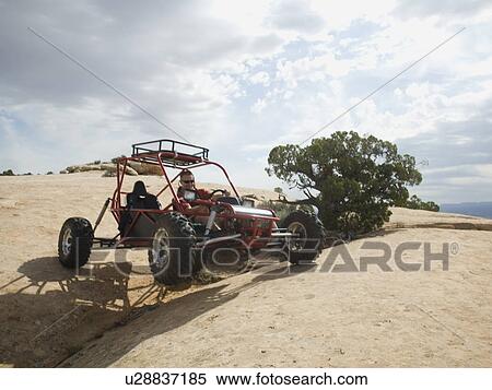Stock Photography - Man in off-road vehicle on rock formation. Fotosearch