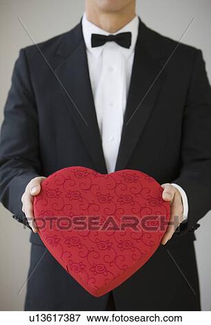 Man in tuxedo holding heart shaped box View Large Photo Image Stock Photo - Man in tuxedo holding heart shaped box. Fotosearch
