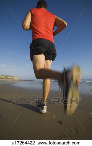 Stock Image - Man jogging on beach. Fotosearch