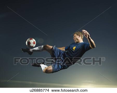 Picture - Man kicking soccer ball in air. Fotosearch