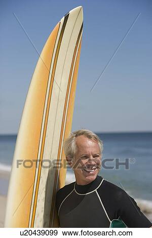 Man next to surfboard at beach View Large Photo Image Stock Photo - Man next to surfboard at beach. Fotosearch