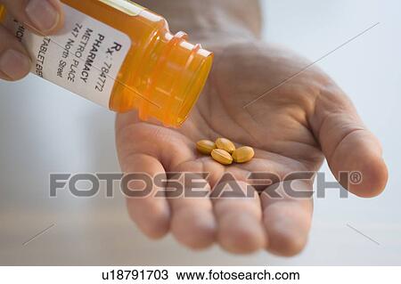 Stock Image - Man pouring prescription medication into hand. Fotosearch