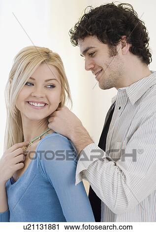 Stock Image - Man putting necklace on girlfriend. Fotosearch