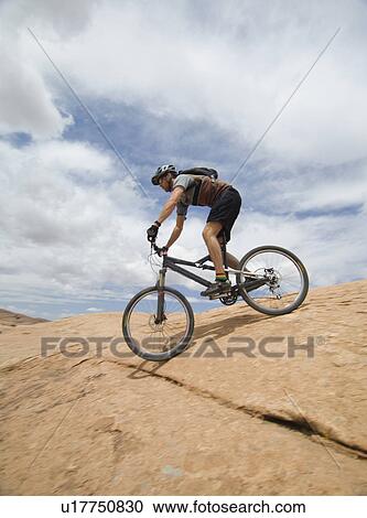 Man riding mountain bike on rock formation View Large Photo Image Stock Image - Man riding mountain bike on rock formation. Fotosearch