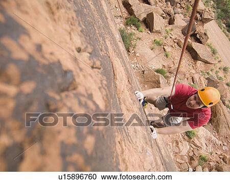 Stock Image - Man rock climbing. Fotosearch