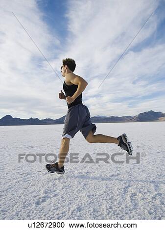 Stock Image - Man running on salt flats, Utah, United States. Fotosearch