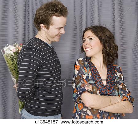 Stock Photo - Man surprising girlfriend with flowers. Fotosearch