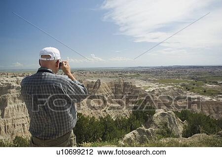 Stock Image - Man taking photograph of canyons. Fotosearch
