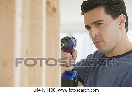 Stock Photograph - Man using cordless drill. Fotosearch