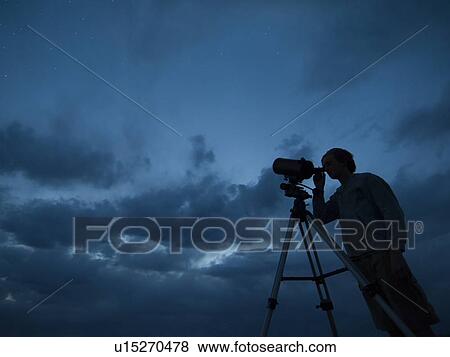 Stock Photo - Man using telescope on tripod. Fotosearch
