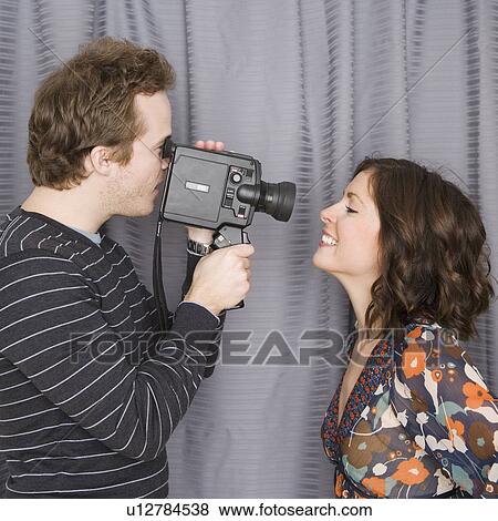 Stock Photo - Man video recording girlfriend’s face. Fotosearch