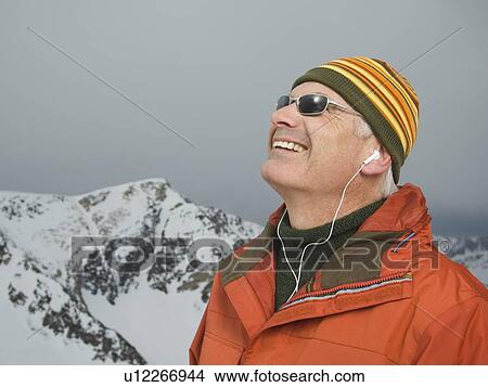 Picture - Man wearing earbuds in mountains. Fotosearch