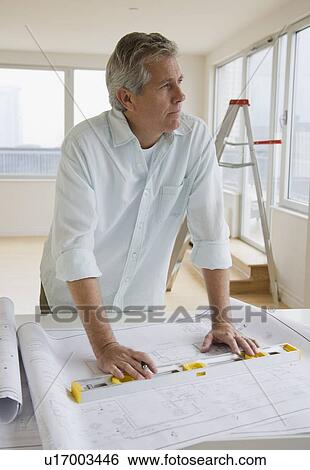 Stock Photograph - Man with level and blueprints. Fotosearch